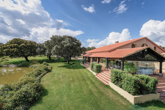 Una de las casas de la finca de las Ahijaderas, con un jardín y un lago