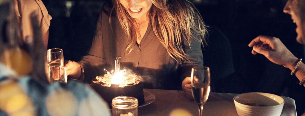 Chica soplando tarta con velas de cumpleaños