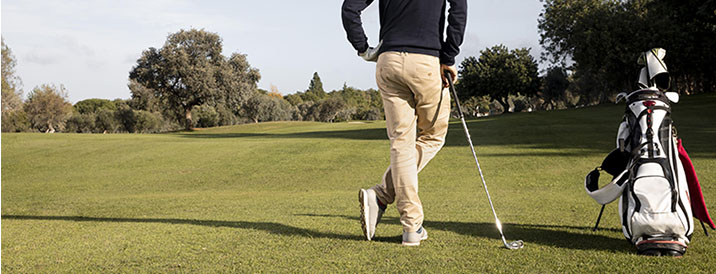 Persona apoyada en un palo de golf esperando su turno