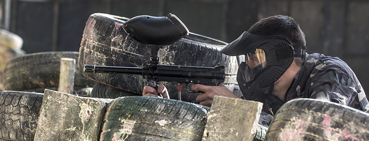 Chico apuntando en una barricada de paintball