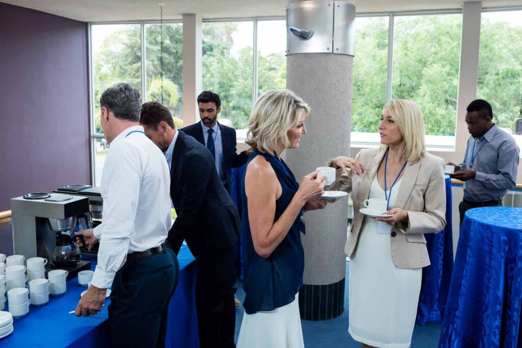 trabajadores de empresa conversando durante pausa para el café en un evento corporativo