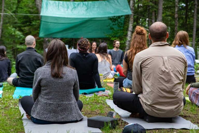 Equipo realizando yoga como actividad de evento corporativo al aire libre